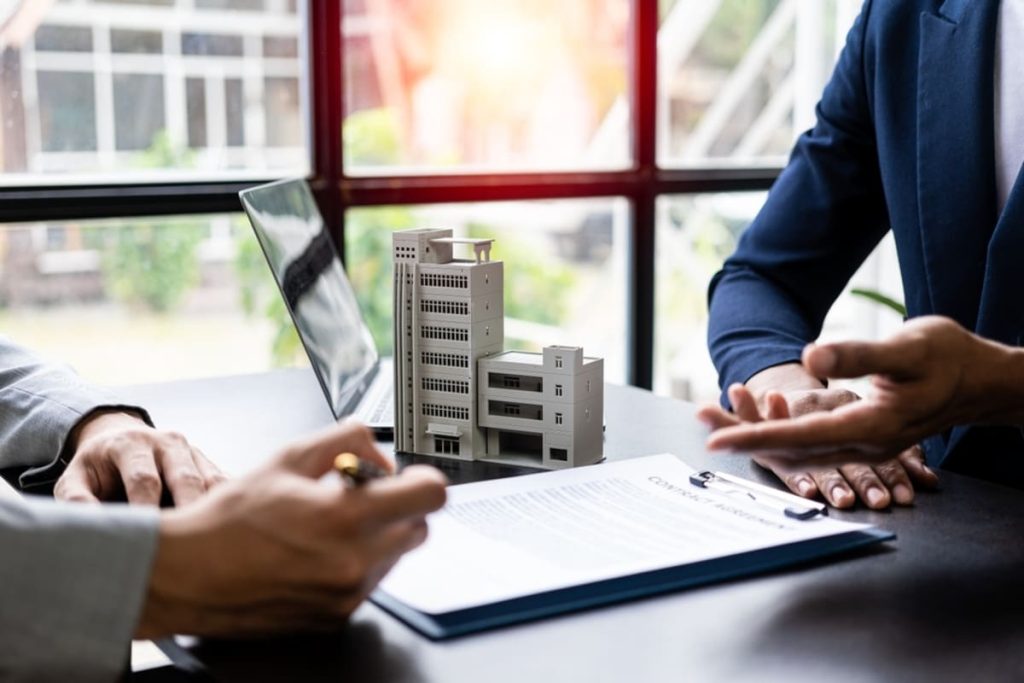 two people talking next to a model commercial building